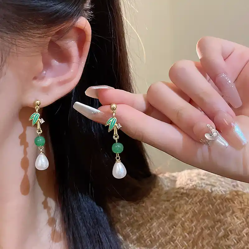 Close-up of Y2K inspired jewelry and 3D crystal-bejeweled manicured nails holding a raw gemstone.